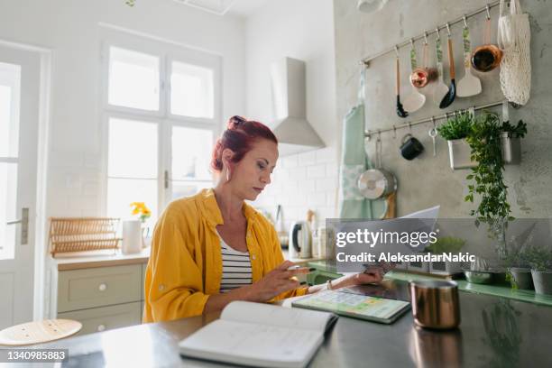 mature woman calculating her income tax - belastingen stockfoto's en -beelden