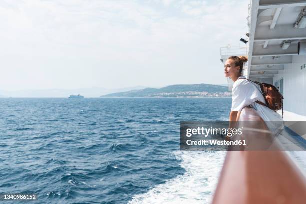 woman wearing backpack looking at sea while standing in boat - fähre stock-fotos und bilder
