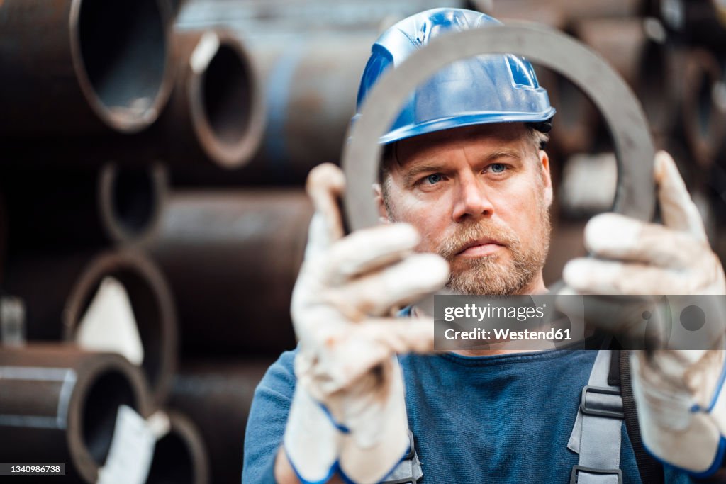 Male inspector checking circle shape steel equipment in warehouse