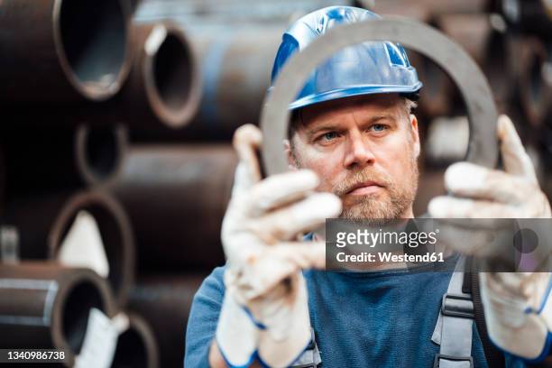 male inspector checking circle shape steel equipment in warehouse - metal industry stockfoto's en -beelden