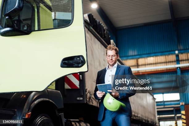 male manager using digital tablet while standing by truck - automotive factory stock pictures, royalty-free photos & images