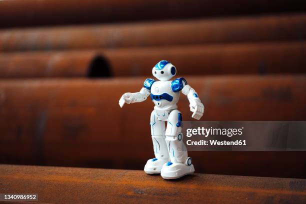 robot toy on rusted pipe in warehouse - figurines stock-fotos und bilder