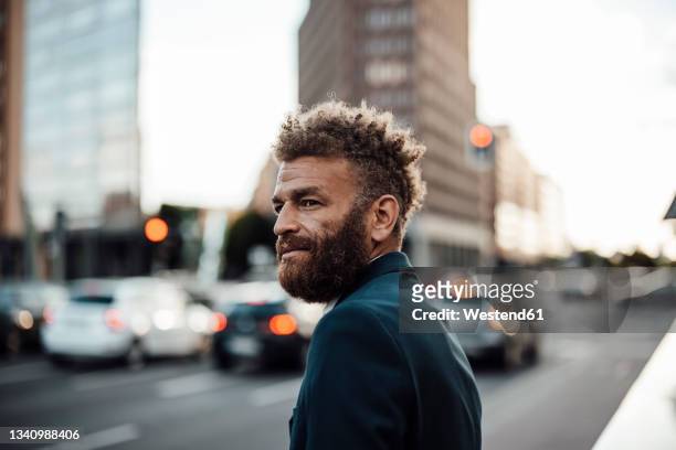 bearded businessman with brown hair at street - variable schärfentiefe stock-fotos und bilder
