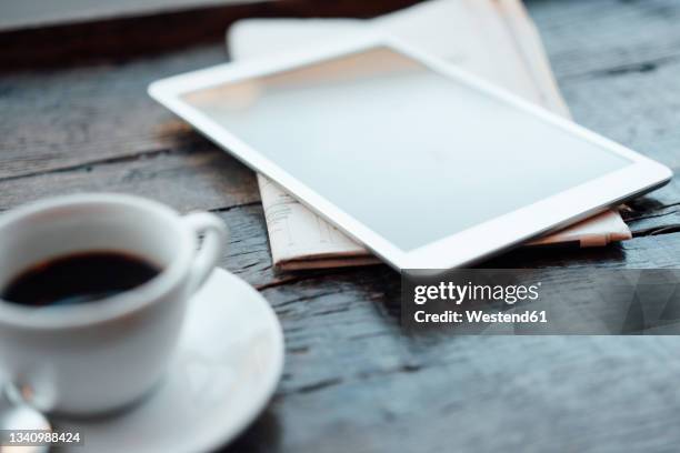 digital tablet with coffee cup and newspaper on table in cafe - digital news ストックフォトと画像