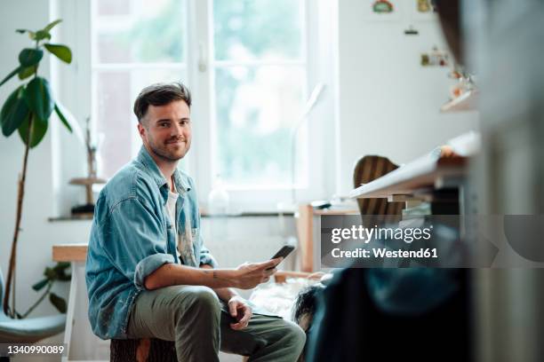 businessman with smart phone sitting at home office - un seul homme d'âge moyen photos et images de collection