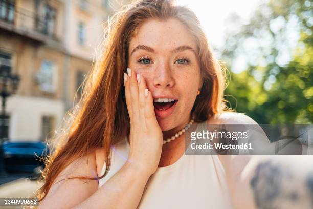 surprised young woman with freckles taking selfie - stupore esterno foto e immagini stock