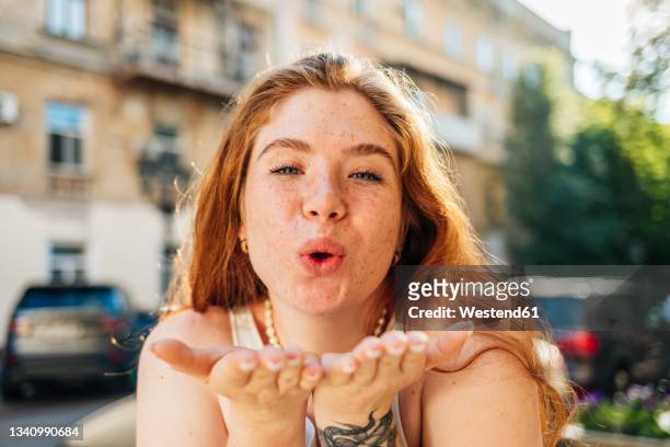 redhead woman gesturing while blowing kiss - puckering 個照片及圖片檔