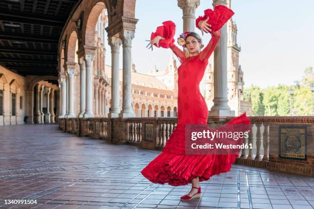 female flamenco artist dancing with hands raised on walkway at plaza de espana, seville, spain - flamenco dancing fotografías e imágenes de stock