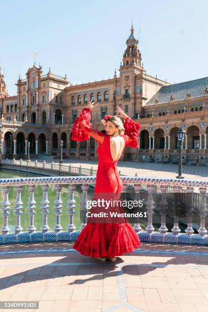 female flamenco dancer dancing with hands raised at plaza de espana in seville, spain - flamencos stock pictures, royalty-free photos & images