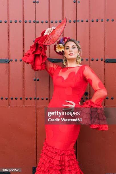 female dancer with traditional dress and hand fan standing in front of door - flamenco stock pictures, royalty-free photos & images