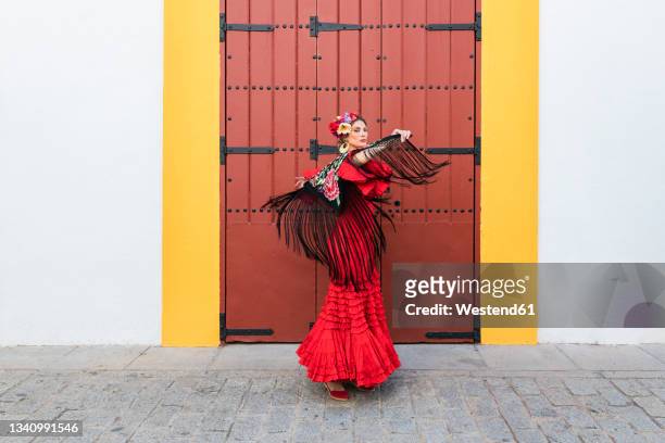 female artist wearing flamenco dress and shawl dancing on footpath - flamencos stock-fotos und bilder
