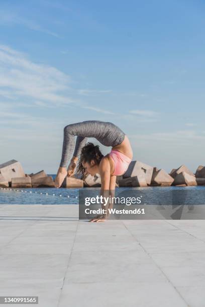 woman practicing vrischikasana on boardwalk - double jointed stock pictures, royalty-free photos & images