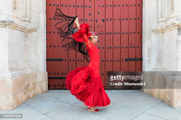 female flamenco dancing with hands raised by door - flamencos stock-fotos und bilder