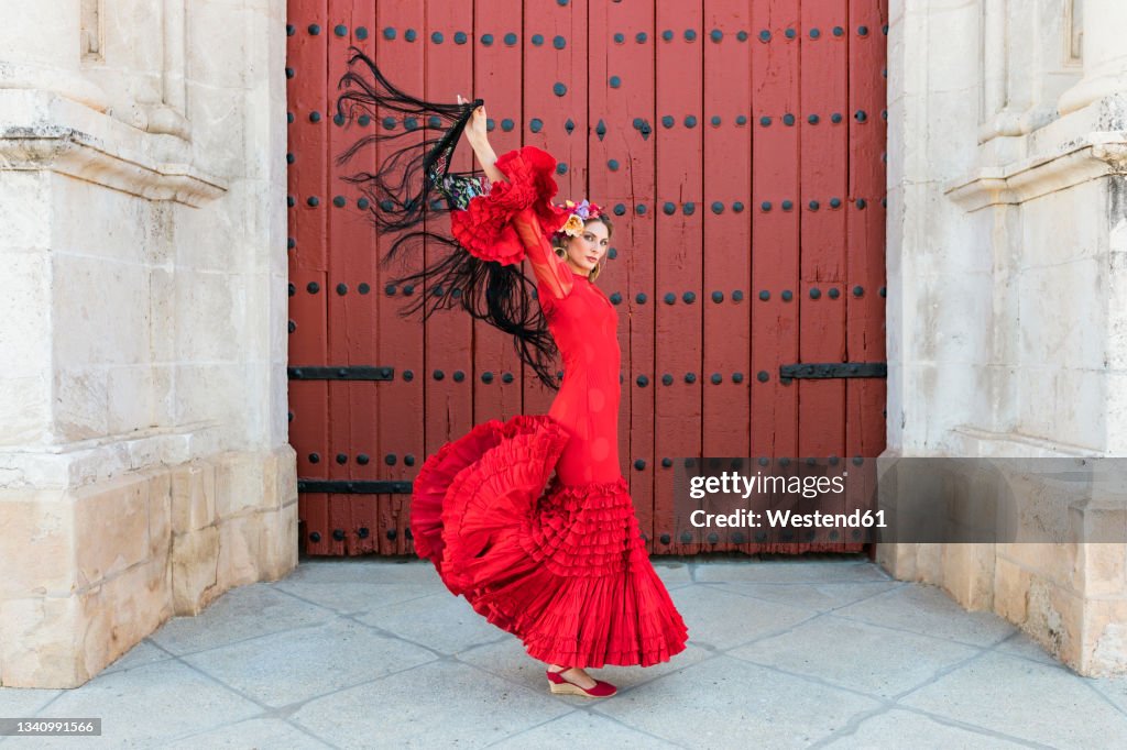 Female flamenco dancing with hands raised by door