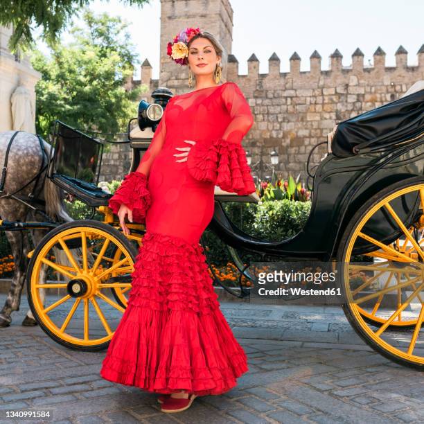 female dancer wearing flamenco dress standing by horse carriage - seville dancing stock pictures, royalty-free photos & images