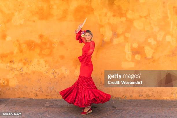female flamenco artist with hand fan dancing on footpath - flamencos stock-fotos und bilder