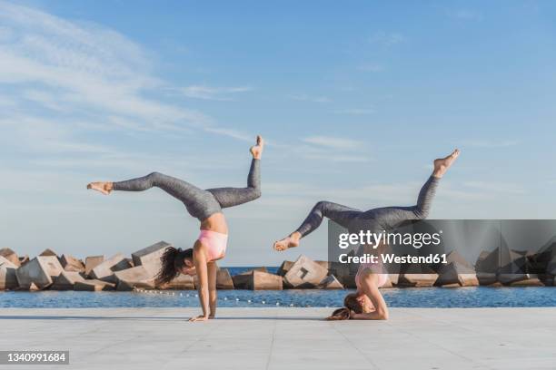 women acrobats exercising on boardwalk - shirshasana stock pictures, royalty-free photos & images