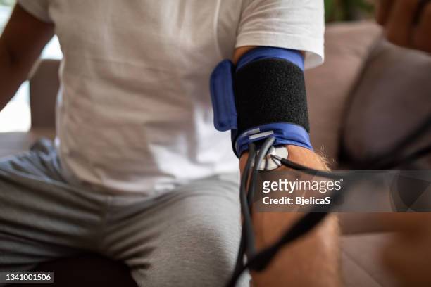 doctor checking patients blood pressure - high blood pressure stock pictures, royalty-free photos & images