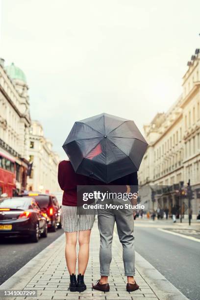 shot of a young couple standing under an umbrella in the city - romance cover stock pictures, royalty-free photos & images