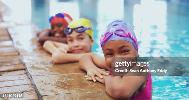 portrait of a group of young children having a swimming lesson in an indoor pool - children swimming stock pictures, royalty-free photos & images