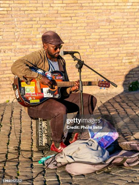 a street musician plays in complete solitude near castel sant'angelo in the heart of rome - sad musician stock pictures, royalty-free photos & images