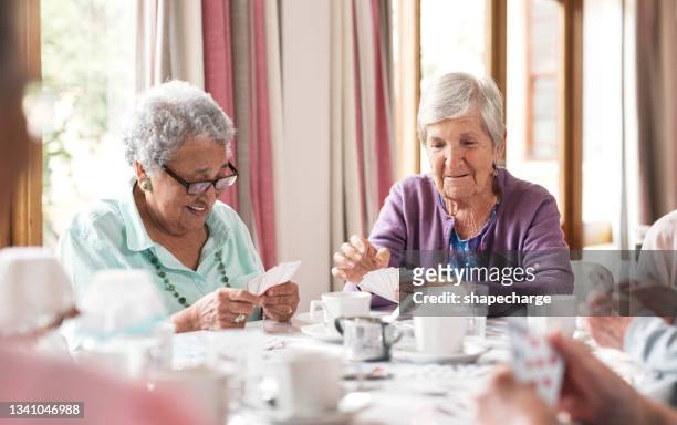 aufnahme einer gruppe älterer frauen, die in einem altersheim zusammen karten spielen - care home stock-fotos und bilder