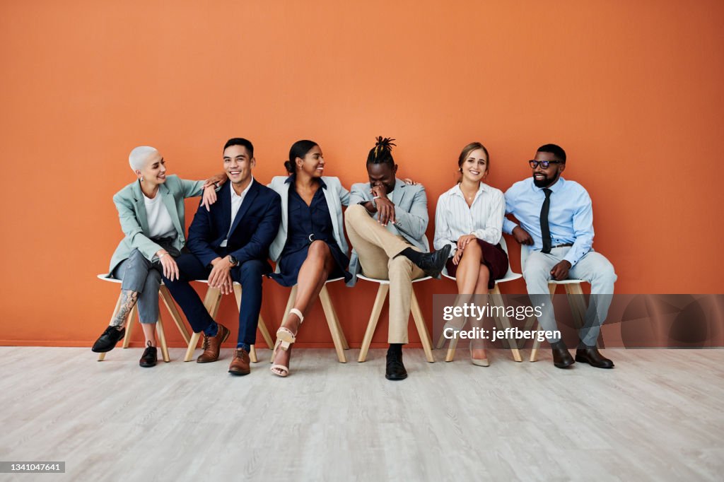 Aufnahme einer Gruppe von Geschäftsleuten, die vor einem orangefarbenen Hintergrund sitzen