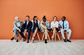 Shot of a group of businesspeople sitting against an orange background