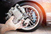 A man holding standard caliper and brake pad spare part in upgrade service maintenance action concept brake system of car