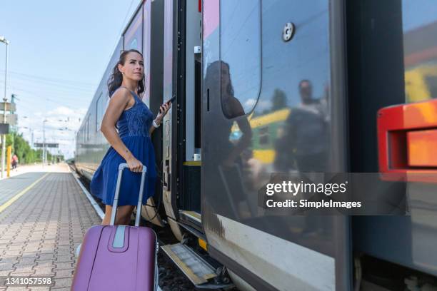 woman checking mobile application before boarding a modern european train with a luggage on a sunny summer day. - hungria - fotografias e filmes do acervo