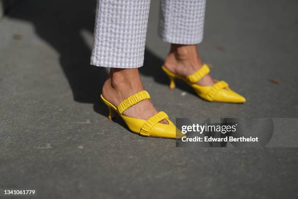 Alexandra Pereira wears pale purple and white checkered pattern large pants, yellow shiny leather pointed pumps heels shoes with two stretch straps,...