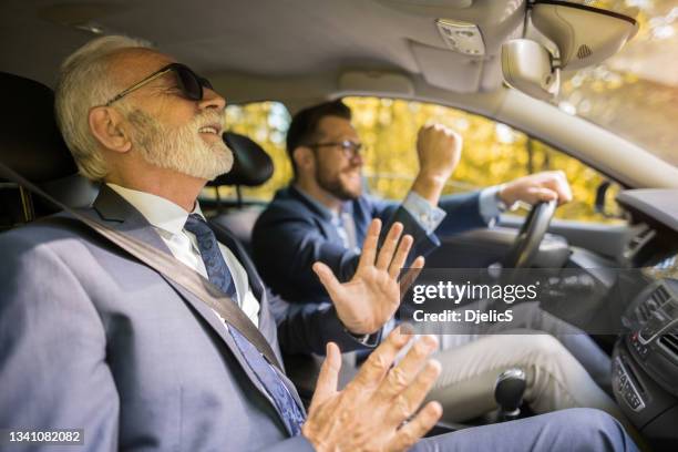 zwei glückliche geschäftsleute, die im auto auf einer malerischen straße unterwegs sind. - auto musik stock-fotos und bilder