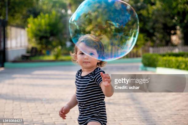 happy carefree toddler boy blowing soap bubbles - bubbles happy stockfoto's en -beelden