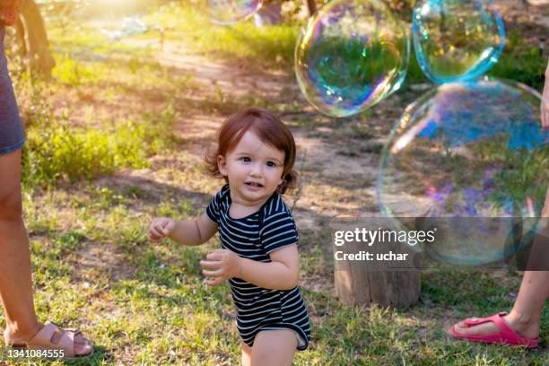 happy carefree toddler boy blowing soap bubbles - bubbles happy stockfoto's en -beelden