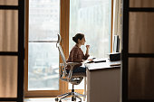 Indian female sit at workplace on ergonomic chair use pc
