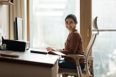 Happy biracial businesswoman freelancer sit by computer at comfy workplace