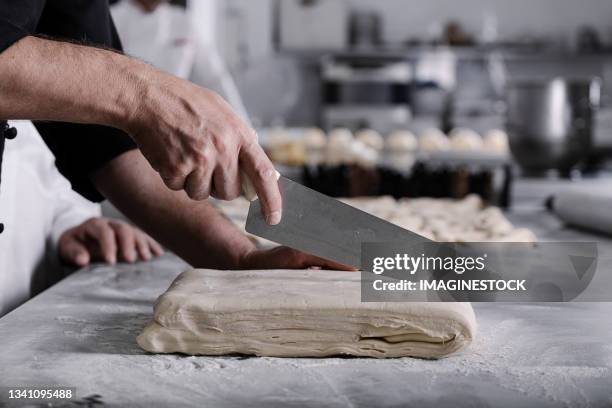 pastry chef cutting the dough with a knife to make puff pastry and cakes. - pastry imagens e fotografias de stock