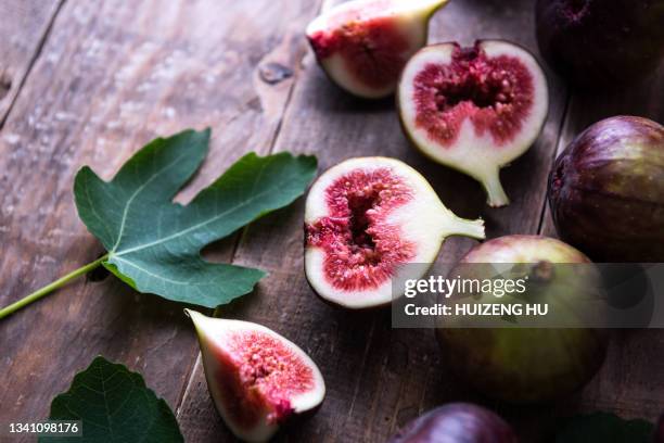 fresh purple fig fruit and slices with leaf on old wooden background - fig stock pictures, royalty-free photos & images