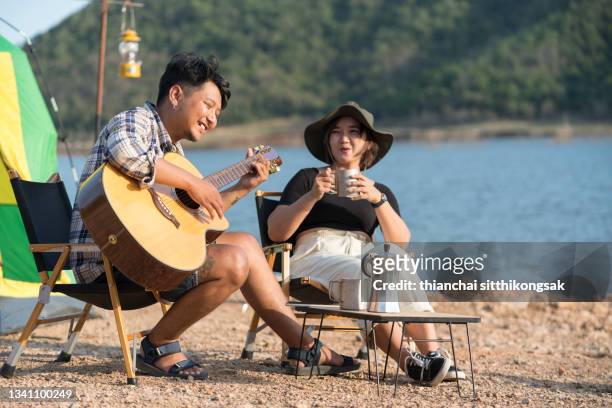 friends enjoying music and playing guitar while relaxing. - couple singing stock pictures, royalty-free photos & images