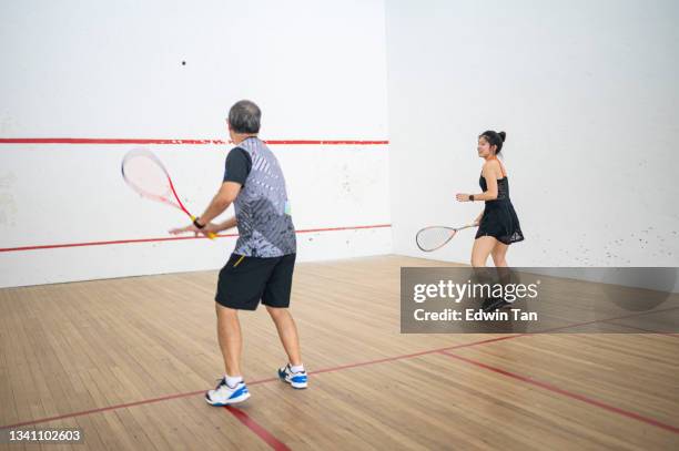 asian squash coach father guiding teaching his daughter squash sport practicing together in squash court - country club stockfoto's en -beelden