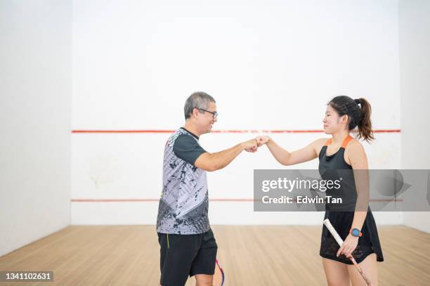 asian squash coach fist bump with his teenage girl student in squash court after the game - racketball stock pictures, royalty-free photos & images