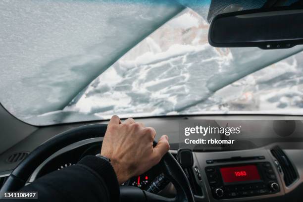 inside view of the car on the windscreen and windshield wipers cleaning snow during a blizzard in winter - extreme weather snow stock pictures, royalty-free photos & images