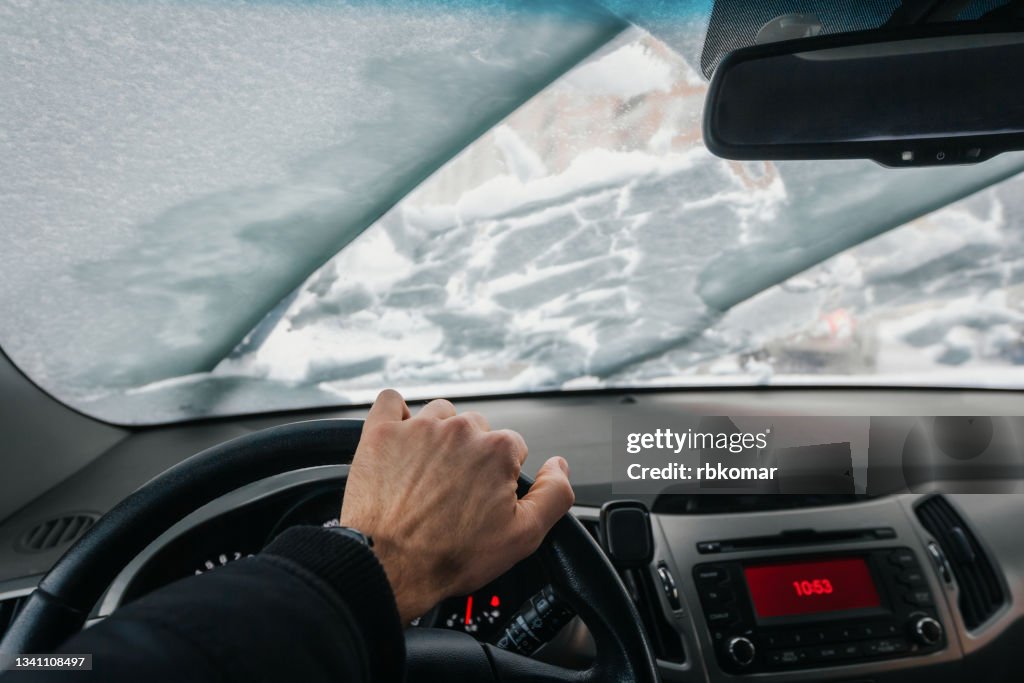 Inside view of the car on the windscreen and windshield wipers cleaning snow during a blizzard in winter