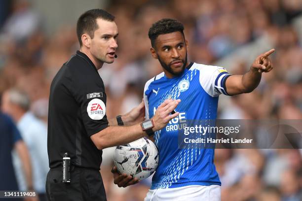 Nathan Thompson of Peterborough United points to the crowd as he speaks with match referee Jarred Gillett, after being provoked by fans during the...