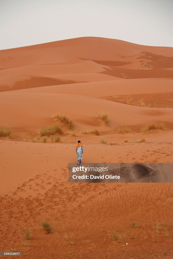 Young man walks alone in orange desert