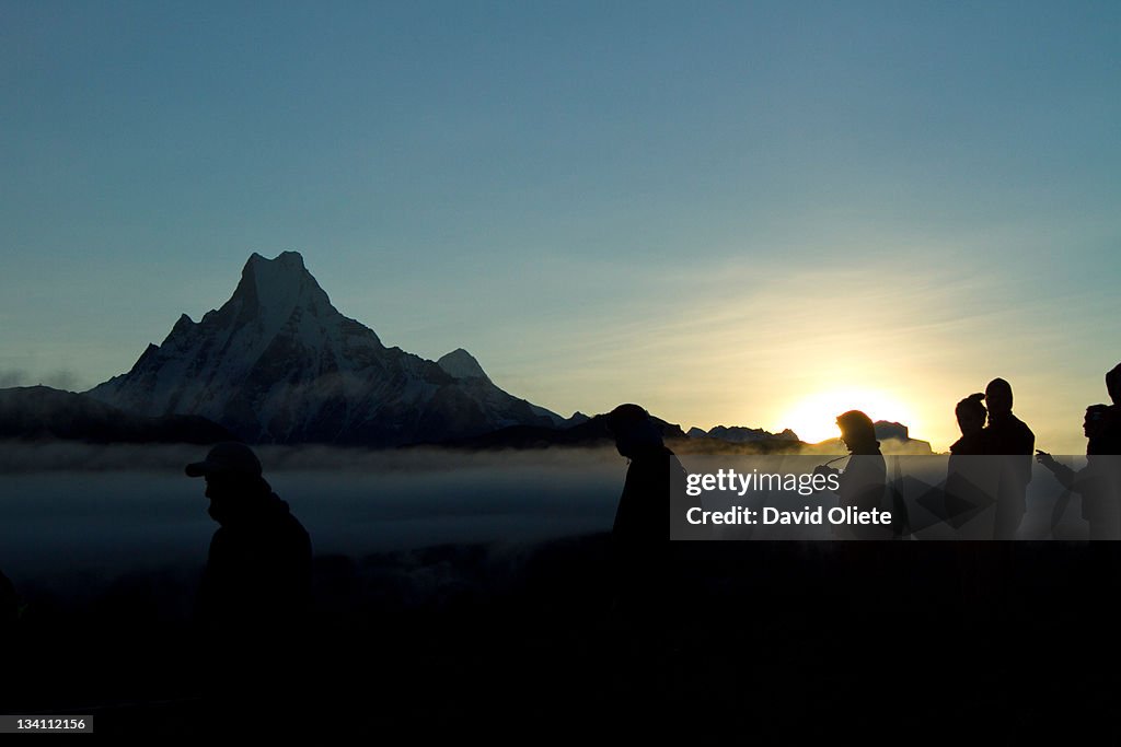 People silhouettes by high mountain at sunrise