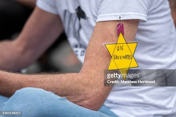 Close-up of a yellow star on the arm of a protestor during a protest against vaccine passports on September 18, 2021 in Cardiff, Wales. First...
