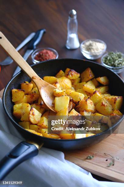 baked in the oven or fried potatoes with spices in a frying pan on a wooden dining or kitchen table. the concept of delicious and healthy homemade food. rustic style. organic vegetables, vegan and vegetarian recipe and diet. - chopped food stock pictures, royalty-free photos & images