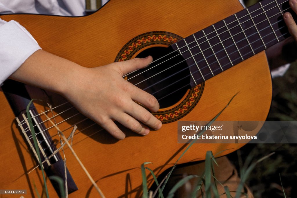The child's hands on the guitar strings. Close-up.