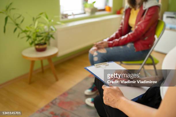 a female psychologist taking notes while talking with a student during a mental therapy - drug rehab stock pictures, royalty-free photos & images